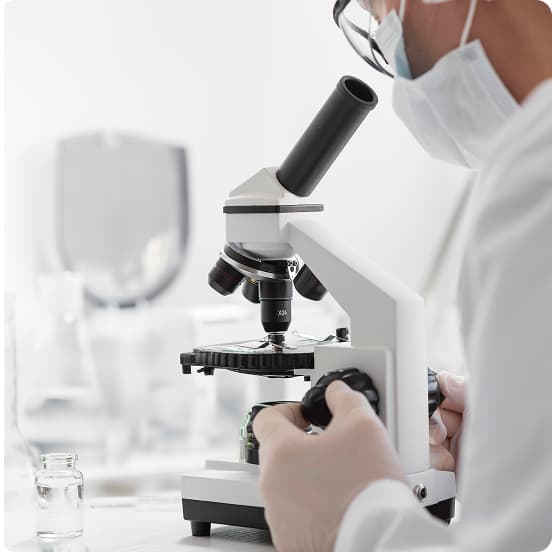 Person using a microscope in a laboratory setting.