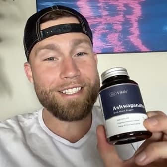 Person holding a bottle labeled 'Ashwagandha with Black Pepper' and smiling.