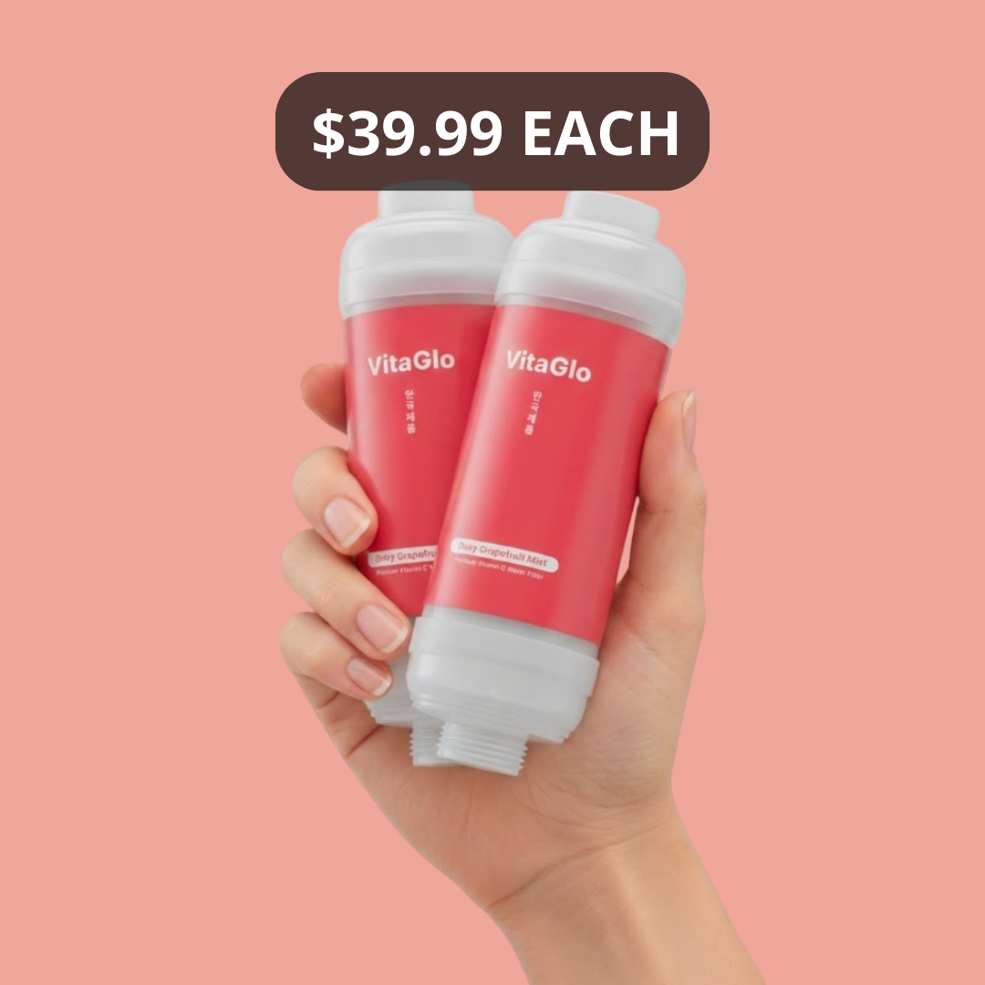 A hand holds two VitaGlo shower filters with red labels against a pink background.