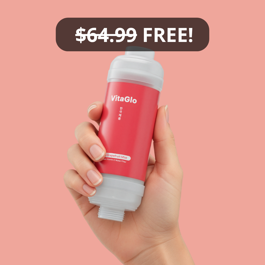 A hand holds a VitaGlo Grapefruit Mist Vitamin C Water Filter against a pink background.