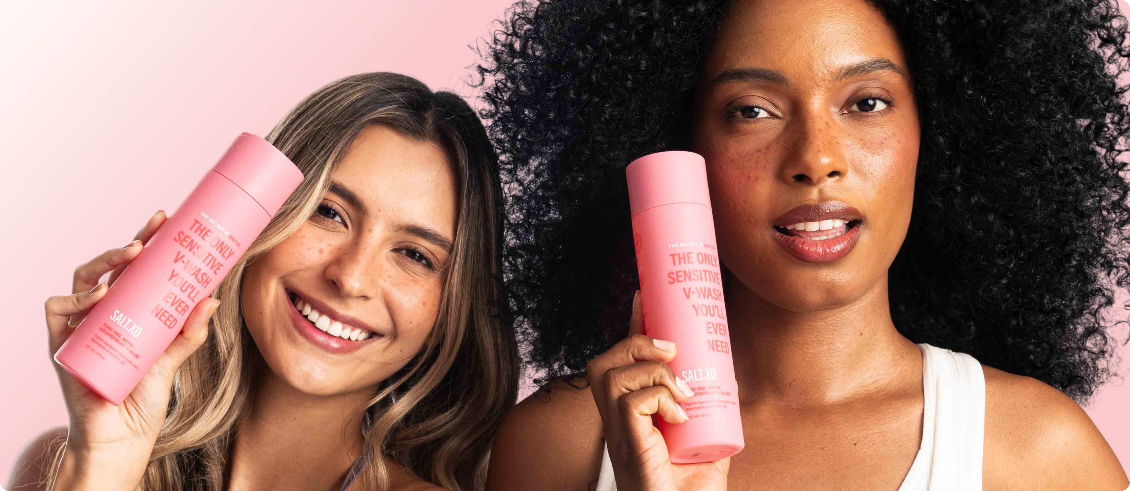 Two smiling women holding pink Salt.xo feminine care bottles – one with blonde hair on the left and one with curly black hair on the right – promoting natural vaginal wellness