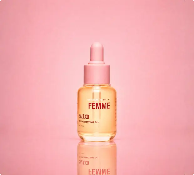 A bottle of rejuvenating oil with a dropper, against a pink background.