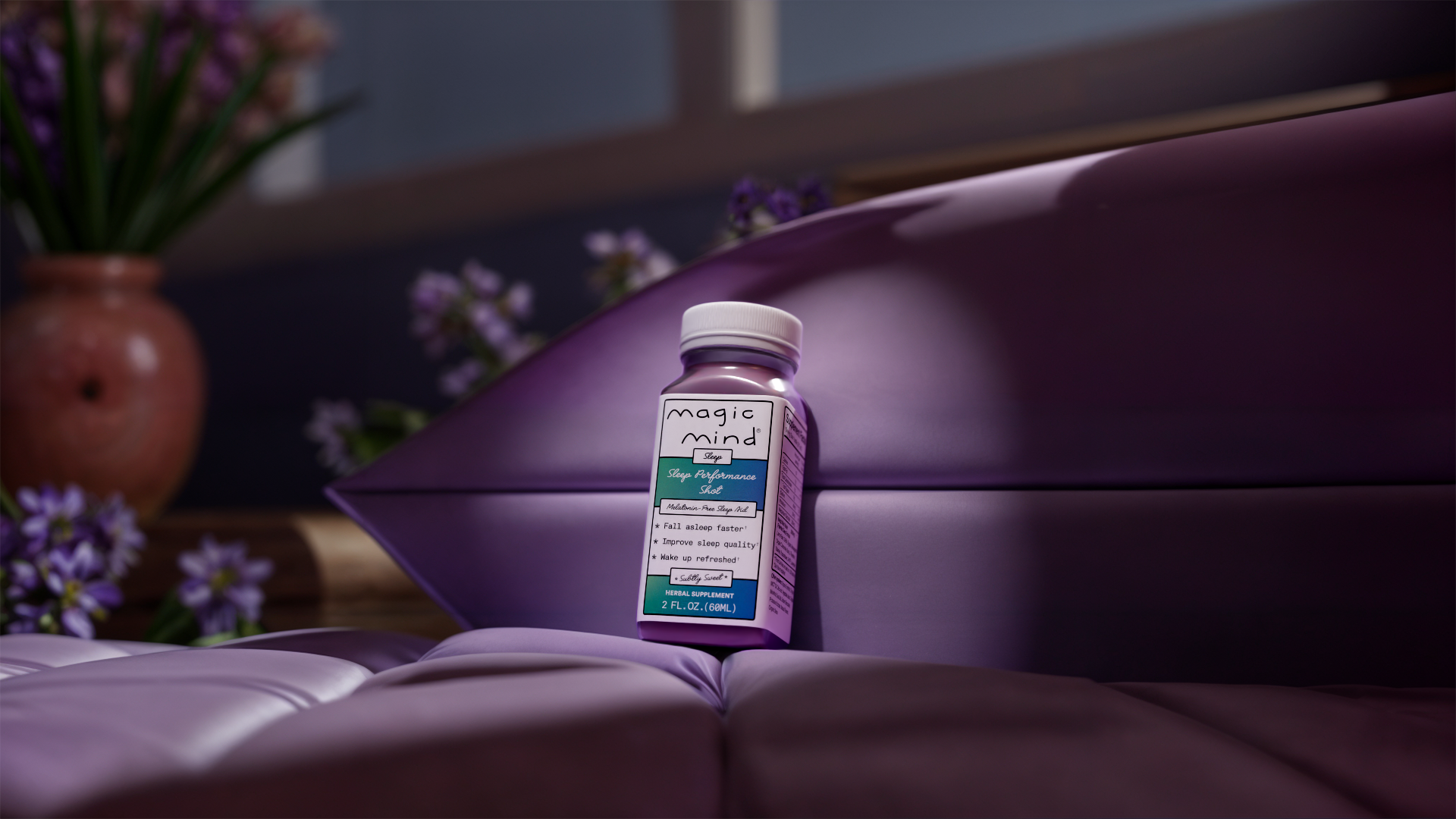 Purple bottle labeled 'magic mind' on a purple cushion with flowers in the background.