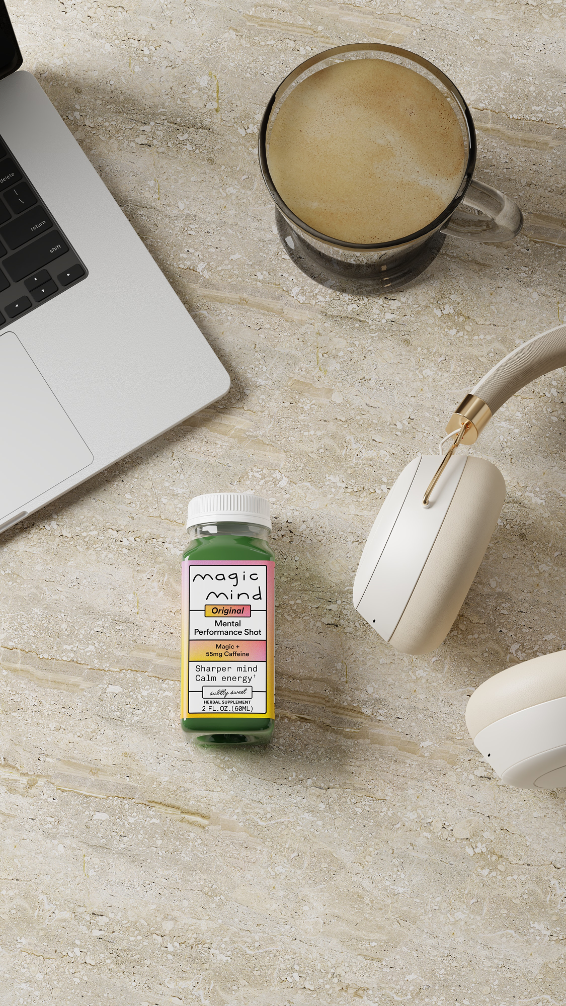 Green bottle, laptop, coffee, and headphones on a stone surface.