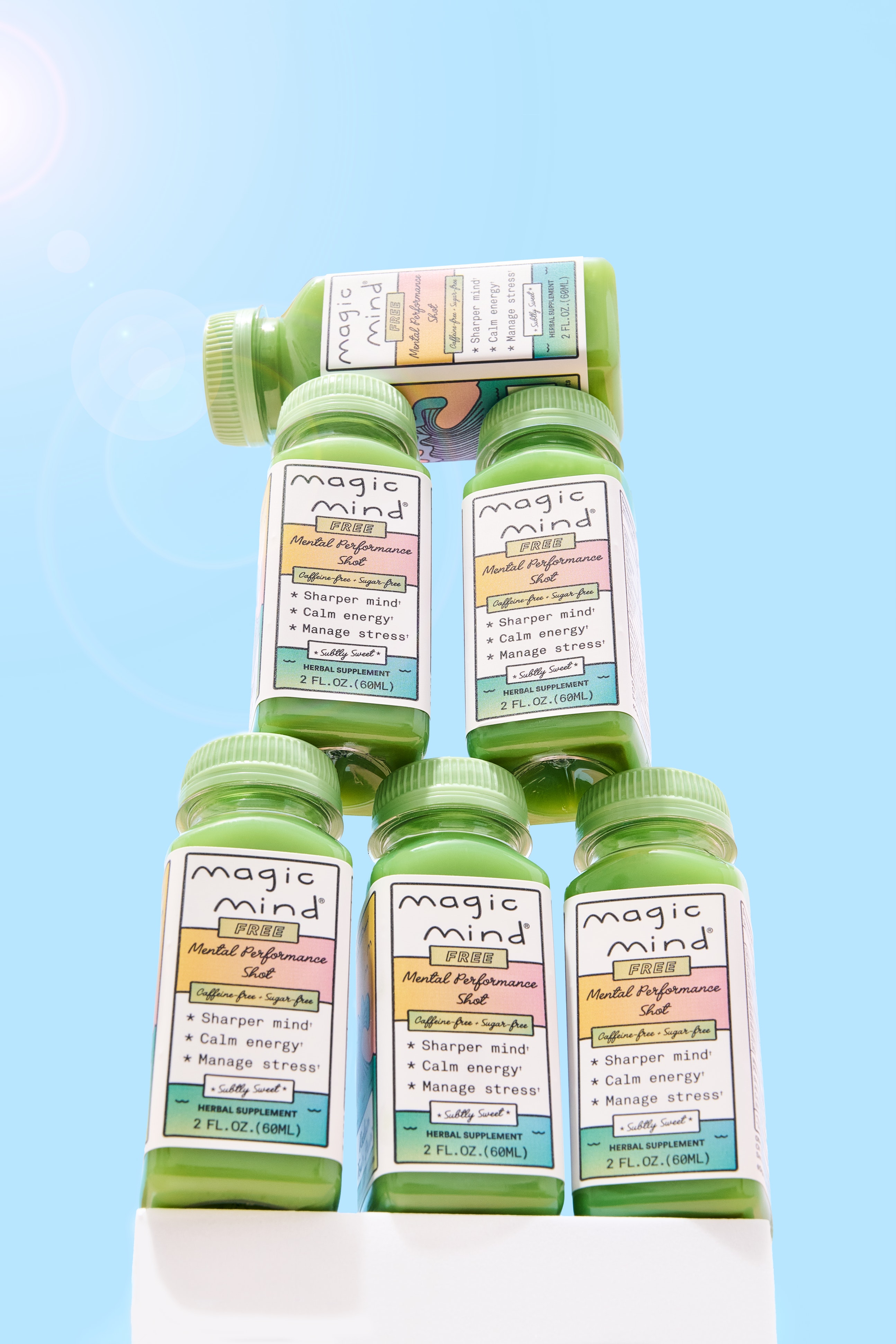 Six green bottles of Magic Mind on a blue background.
