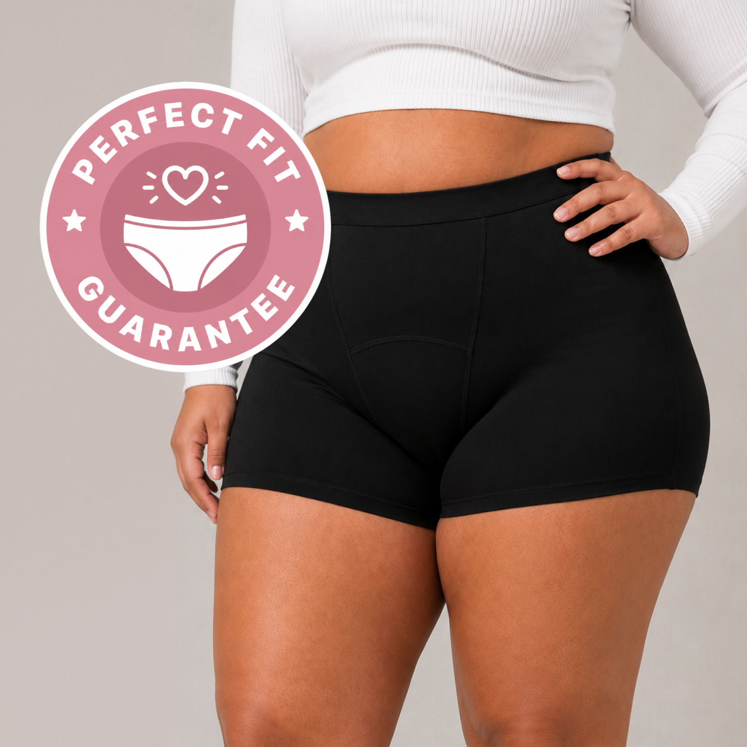 A person wearing black boy shorts and a white long-sleeved top, with a 'Perfect Fit Guarantee' badge.