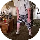 A person wearing shorts and a t-shirt bends over with their hands on their knees inside a room.