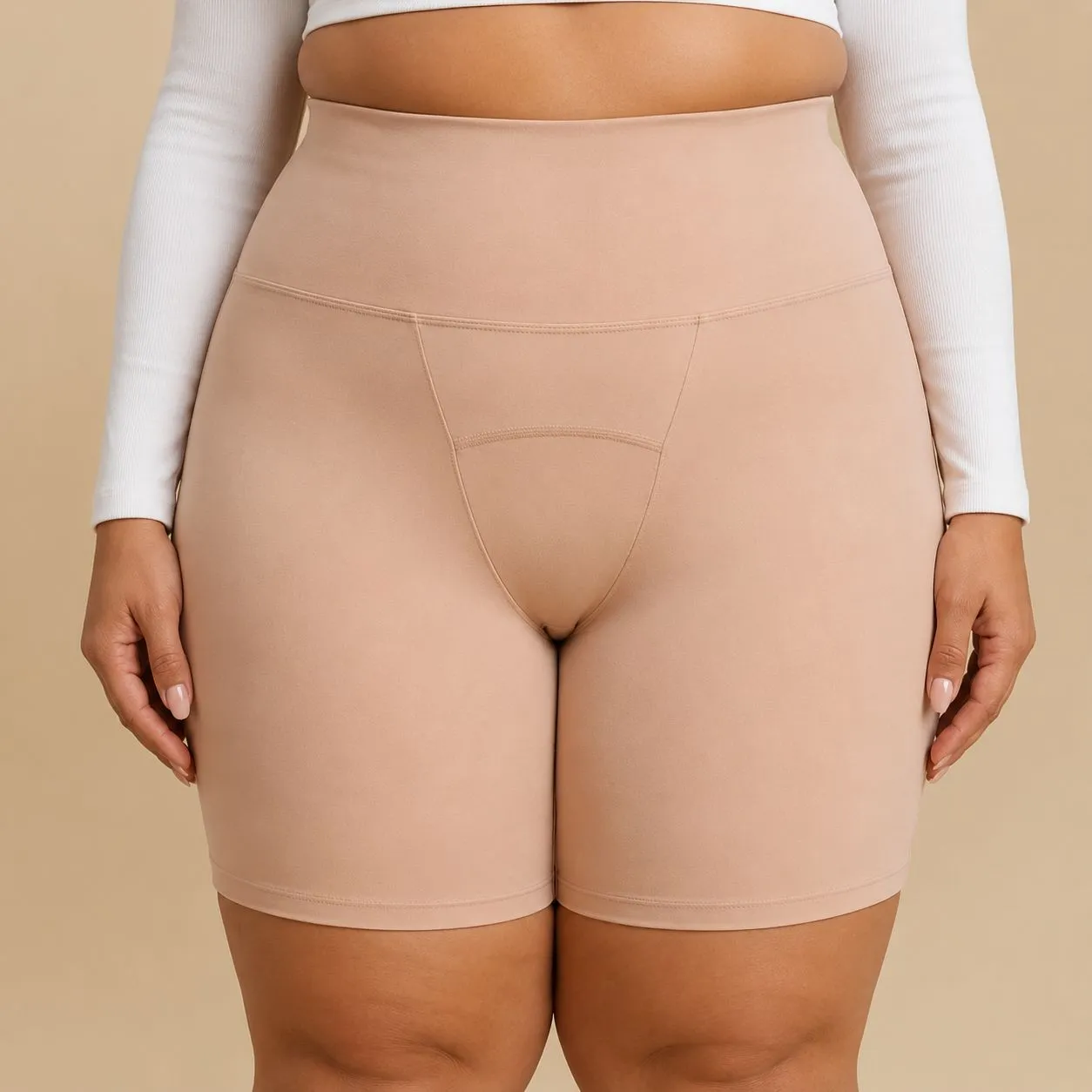 A person wears a white long-sleeved top and high-waisted, nude-colored shorts.