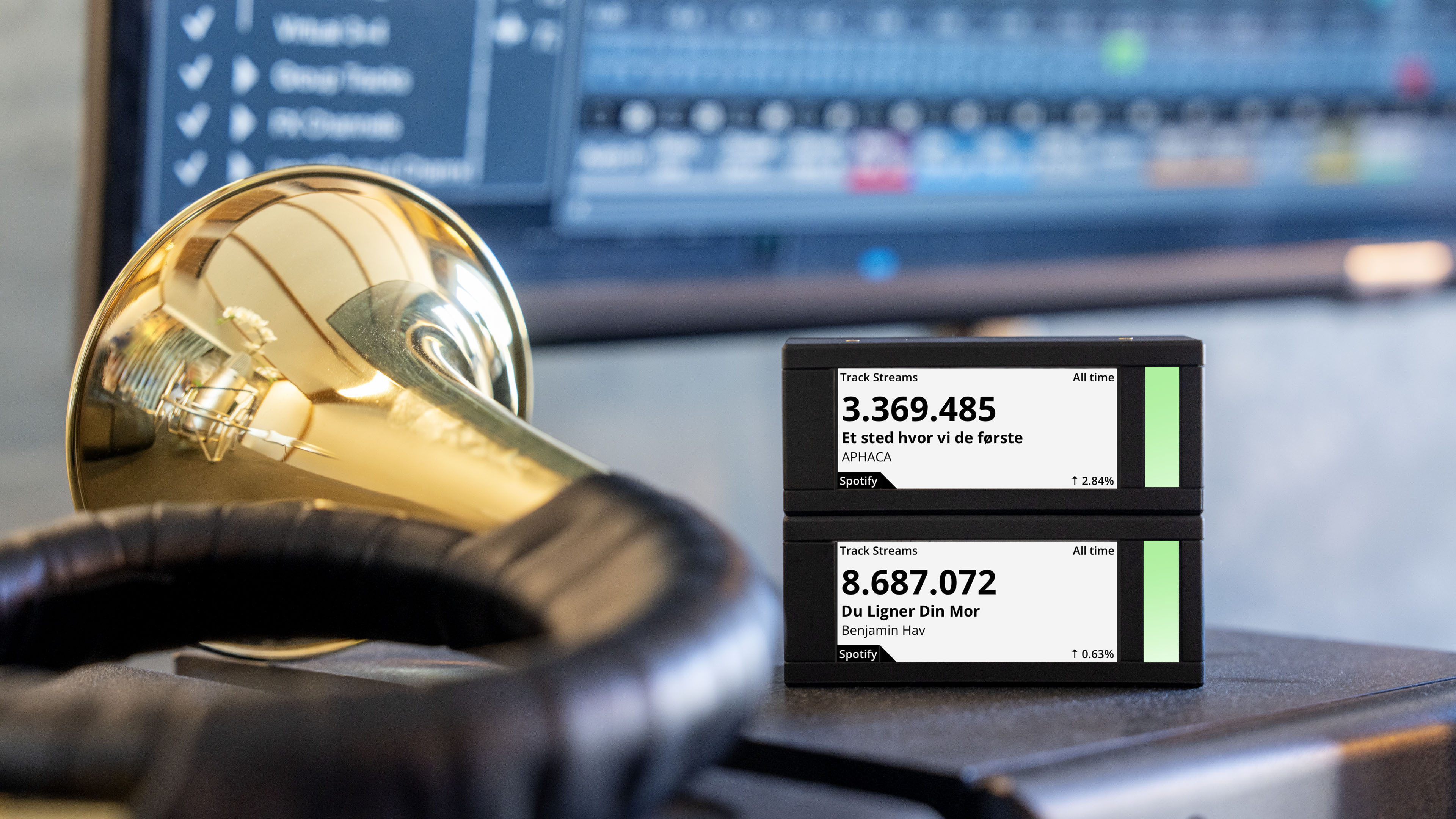 A brass instrument, headphones, and digital displays showing Spotify track streams.