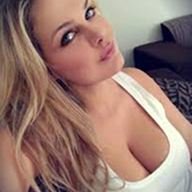 A close-up photo of a blonde woman with light-colored eyes wearing a white tank top.
