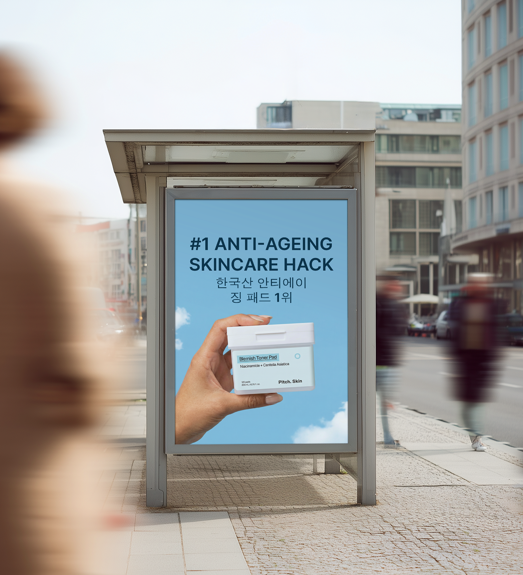 An advertisement for a skincare product in a bus stop shelter on a city street.