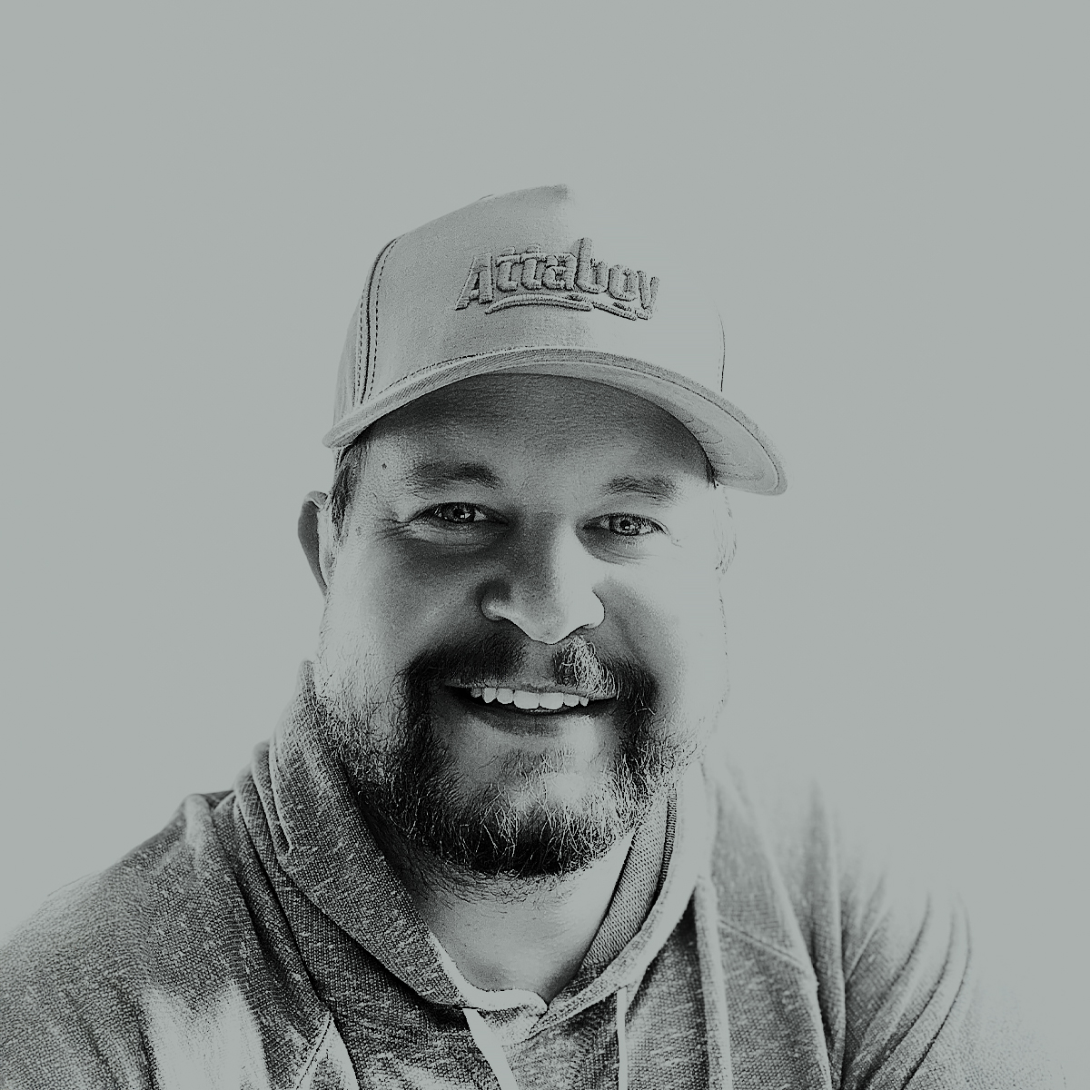 Smiling person wearing a cap and hoodie, black and white image.