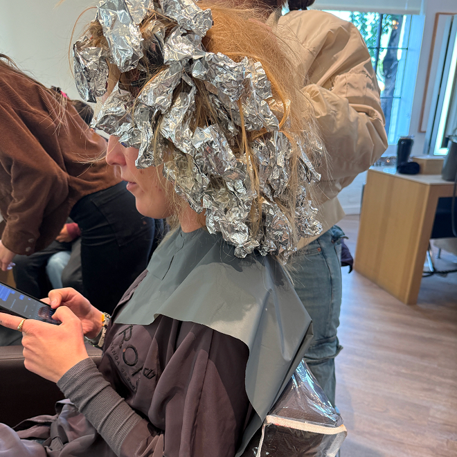 Person applying hair dye with foil wraps in a salon.