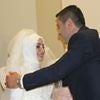 A bride and groom embracing, the bride in a white dress and veil.