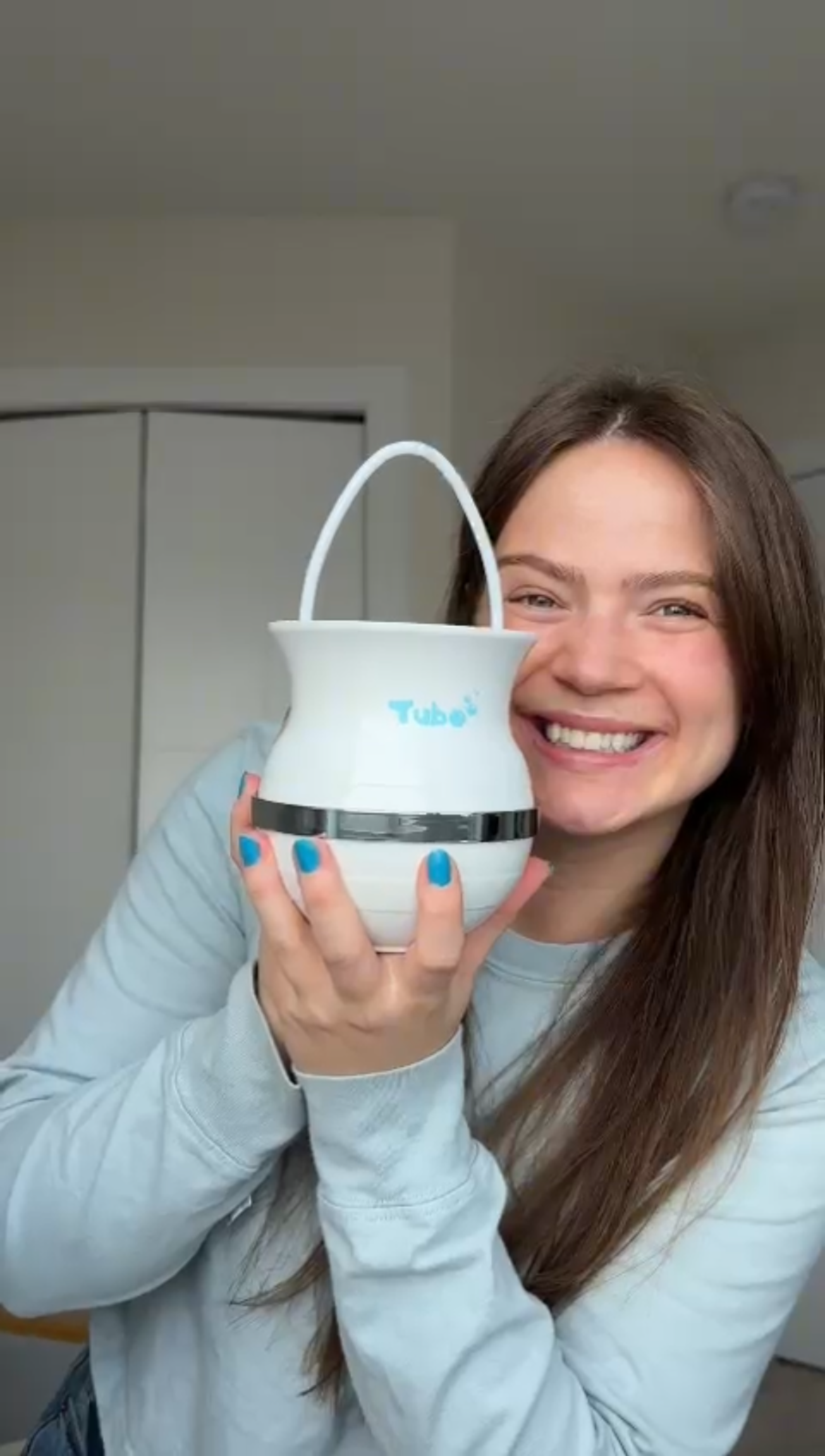 Person smiling, holding a white container with a handle.