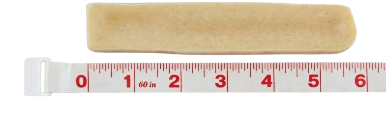 A rectangular, light-brown chew is shown above a white measuring tape, indicating a length of over five inches.