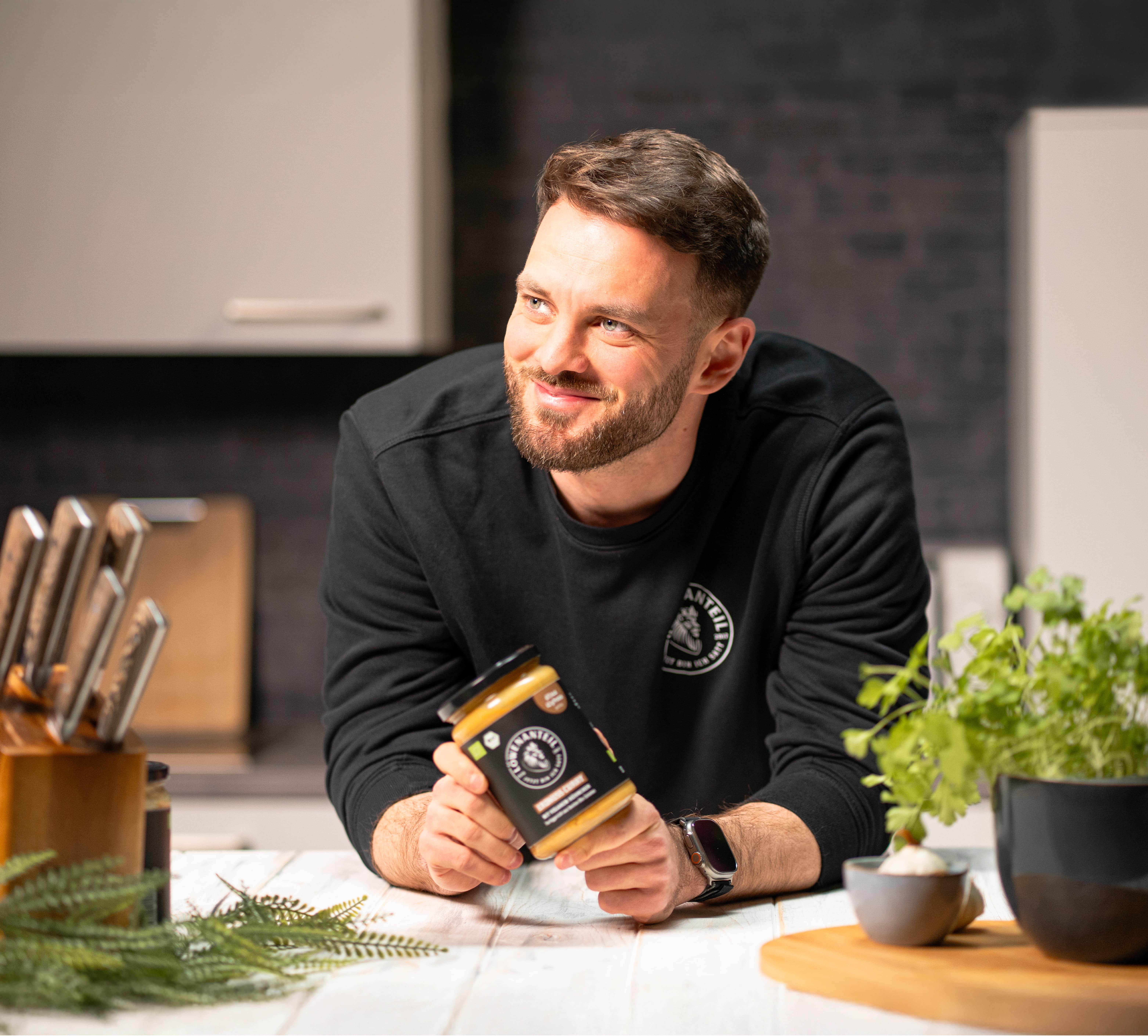 Person holding a jar in a modern kitchen with herbs and a knife block.
