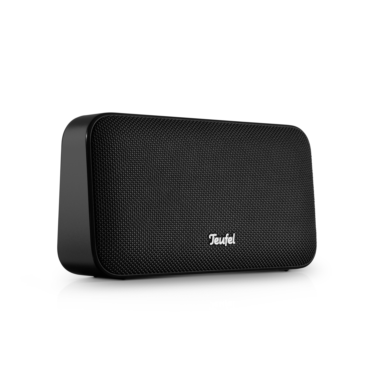 A black Teufel portable speaker with a textured grille, angled on a white reflective surface.