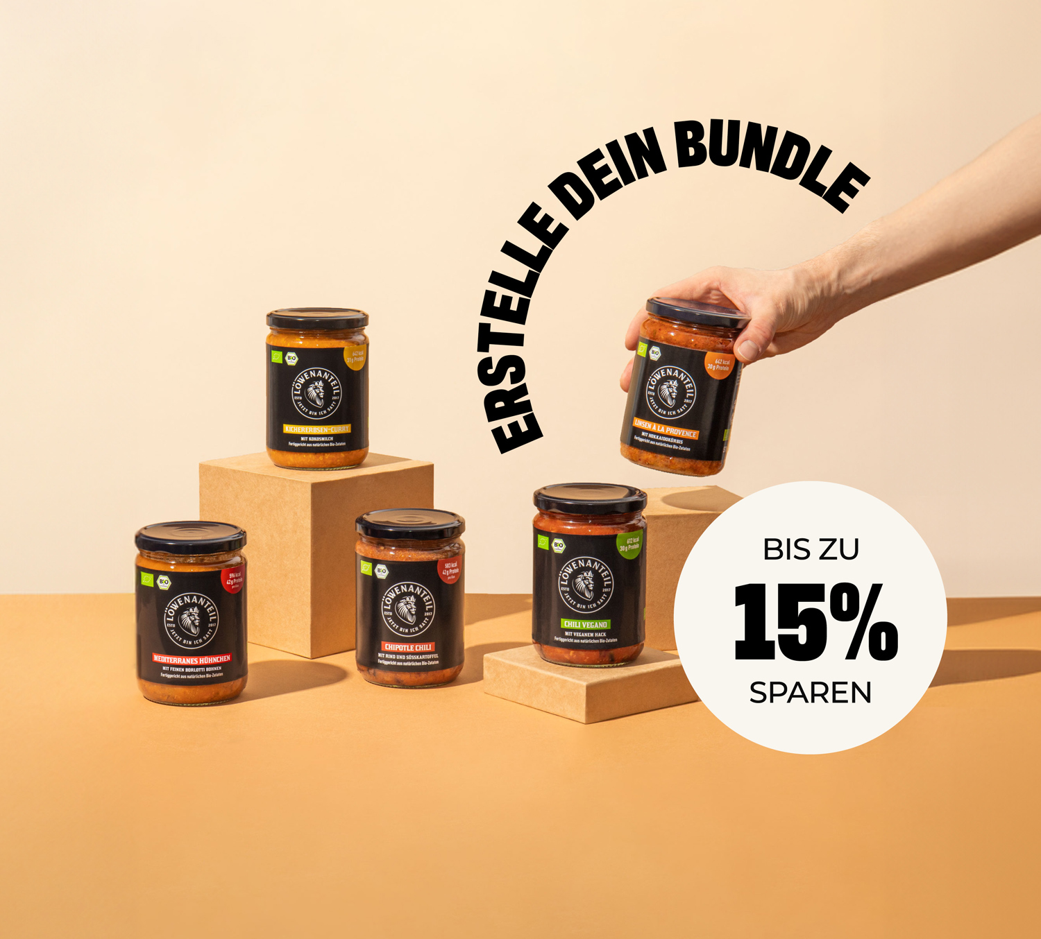 A hand picks up one of five jars of Löwenanteil food products displayed on blocks.