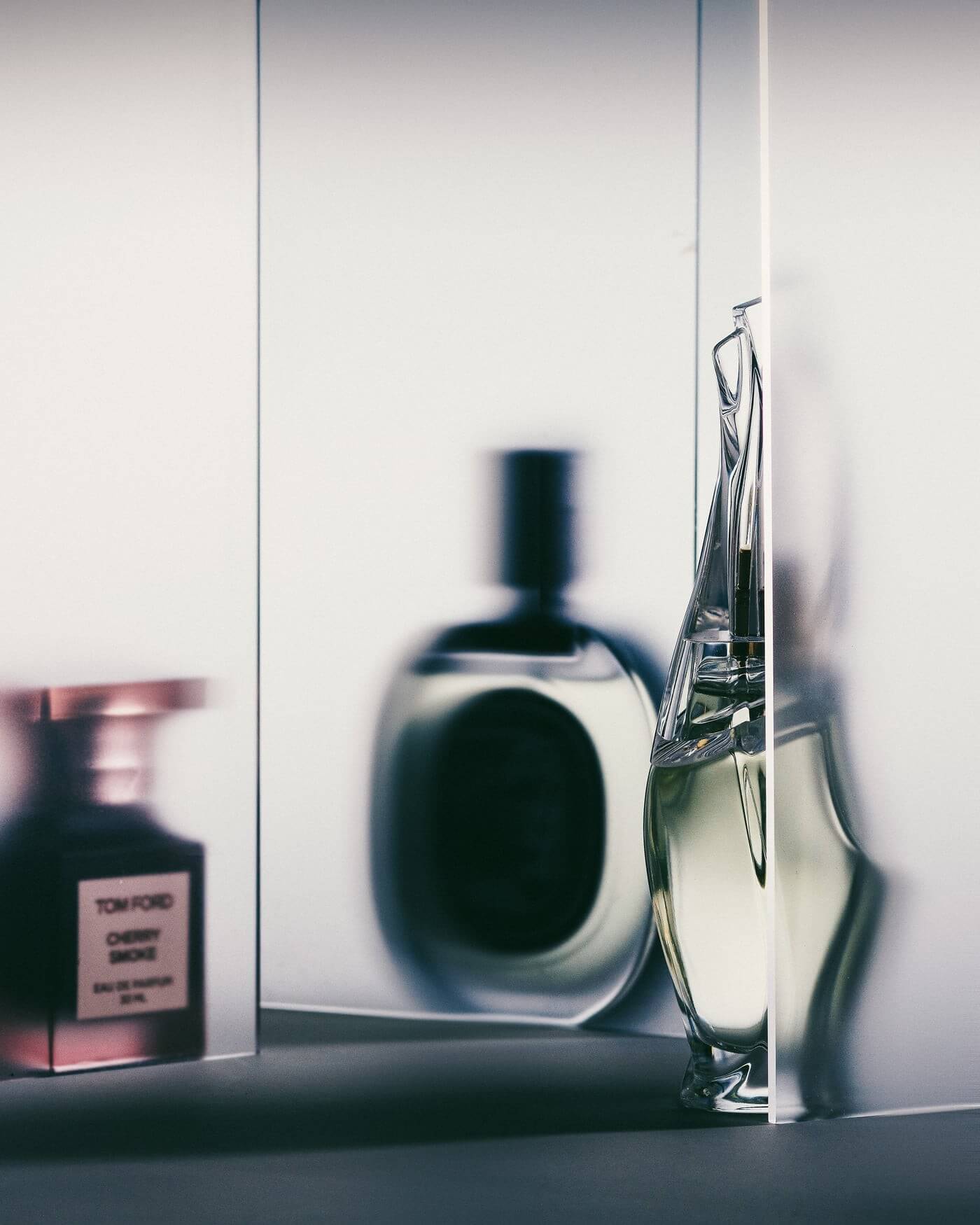 modern perfume bottles behind glass with minimal reflections, illustrating fragrance oil versatility for candles, soaps, and lotions