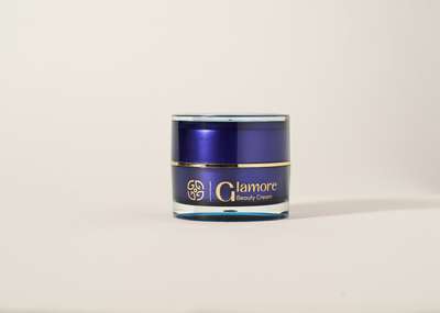 A small, cylindrical blue and gold jar of Glamore Beauty Cream against a plain background.