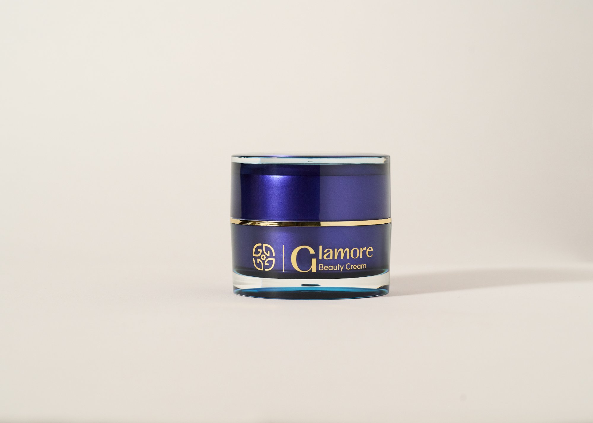 A blue and gold jar of Glamore Beauty Cream sits against a plain, off-white background.