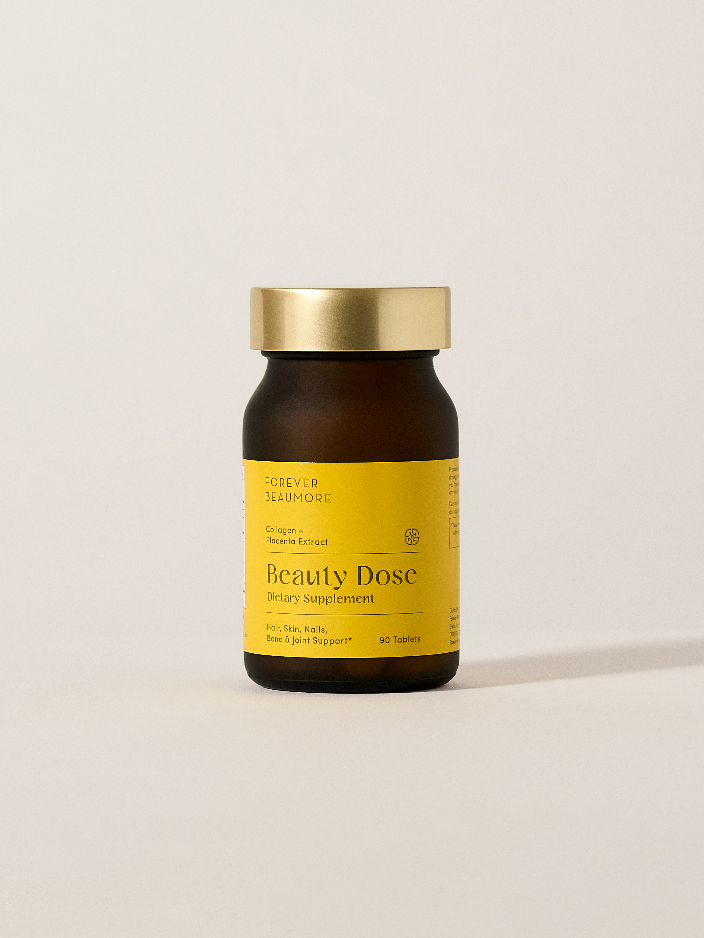 A brown bottle of Forever Beaumore Beauty Dose dietary supplement with a gold cap on a white background.