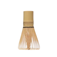 A traditional bamboo matcha whisk, known as a chasen, standing upright against a white background.