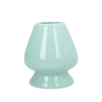 A light green ceramic matcha whisk holder on a white background.