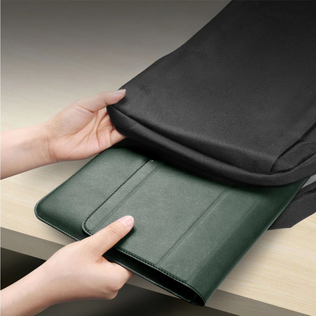 Hands placing a green leather folder into a black bag.