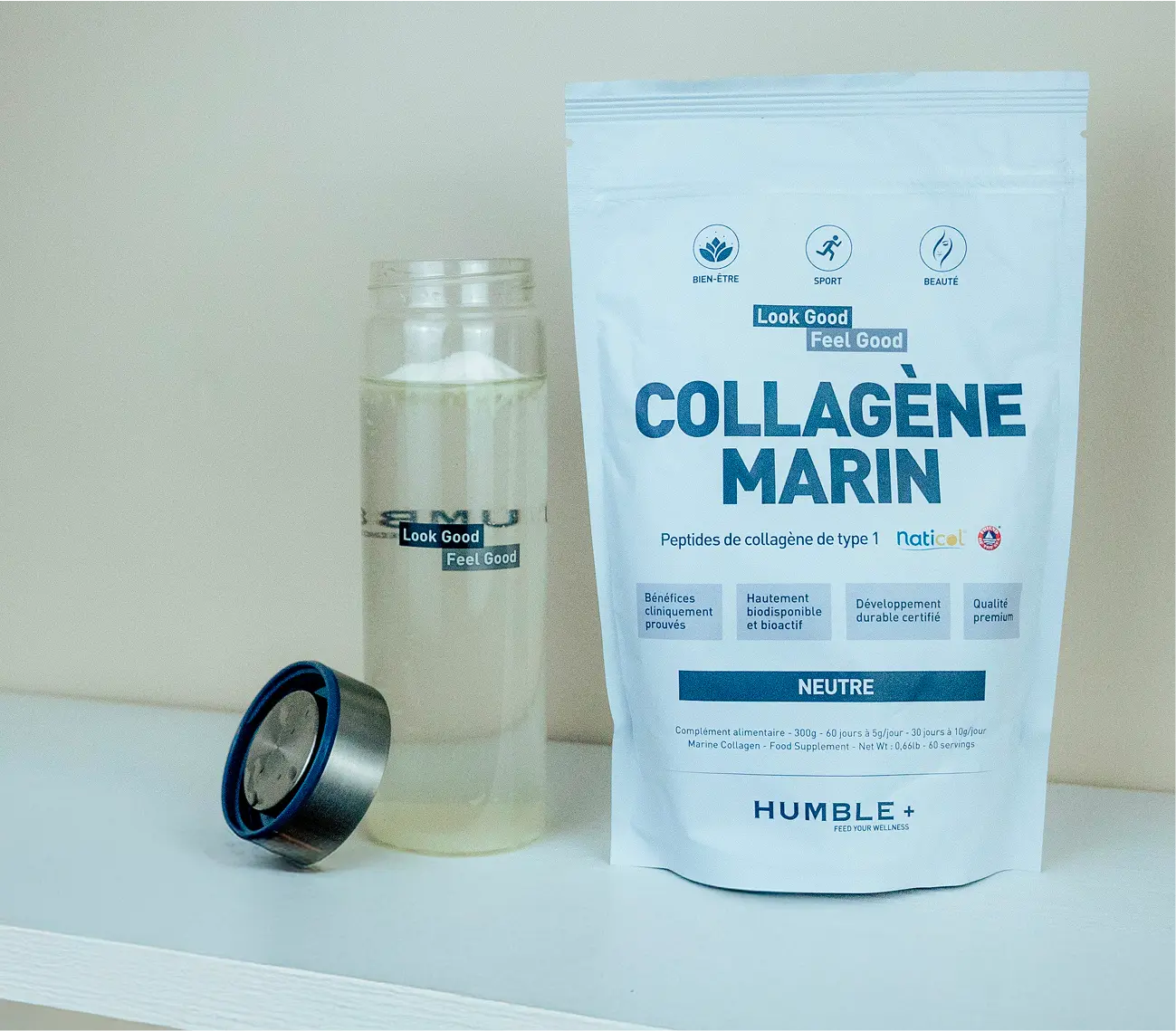 A white pouch of Humble+ Marine Collagen sits next to a clear glass bottle of water.