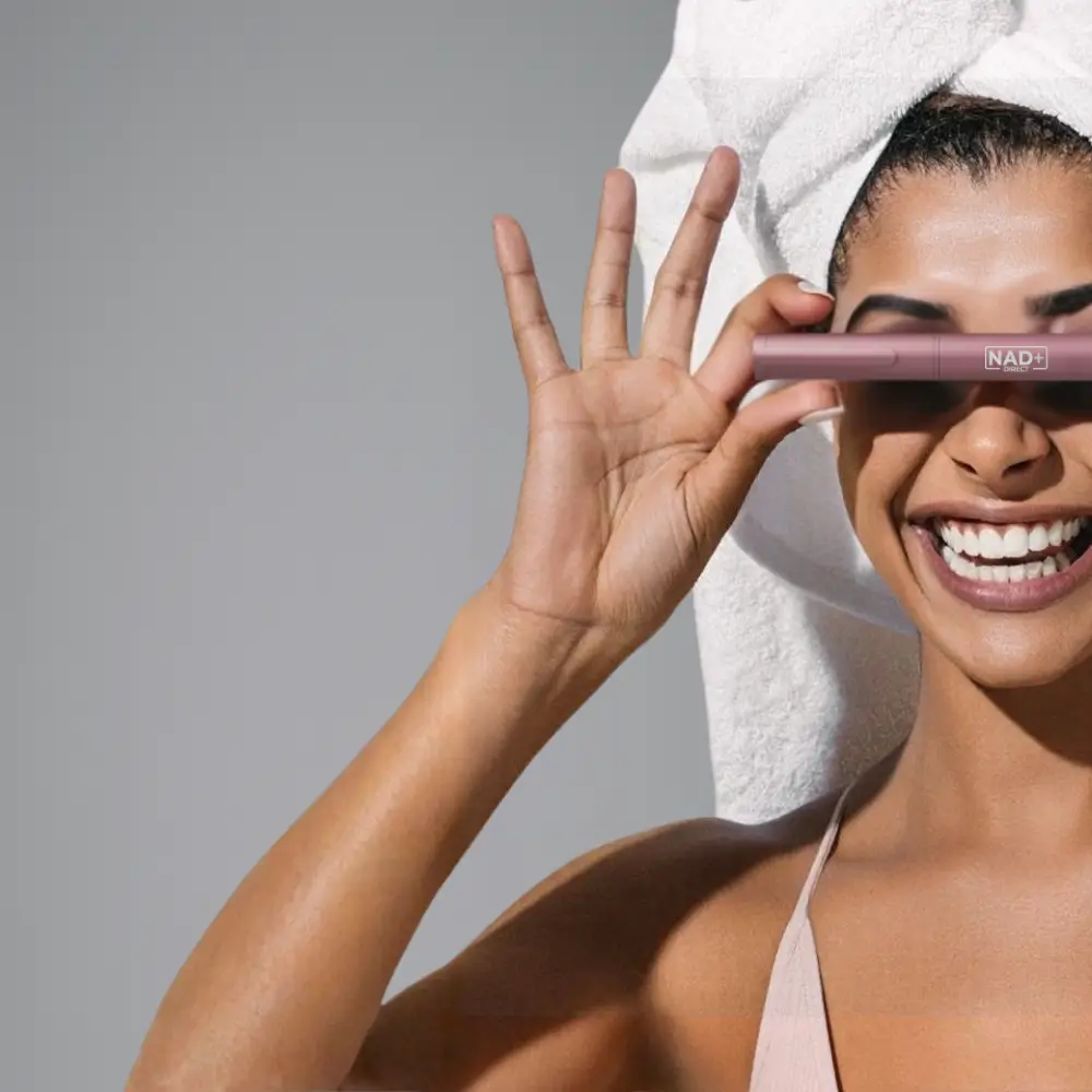 Person with a towel on head holding a cosmetic product.