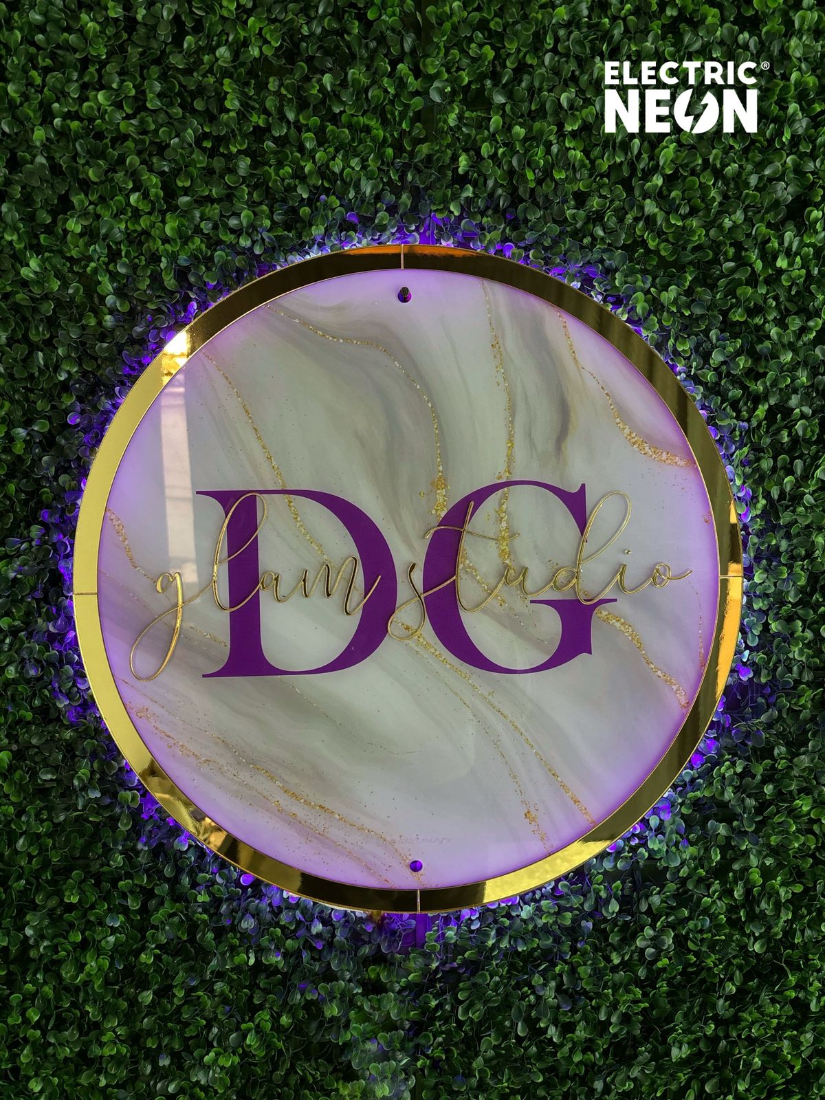 Circular sign with 'DG glam studio' on a leafy background.