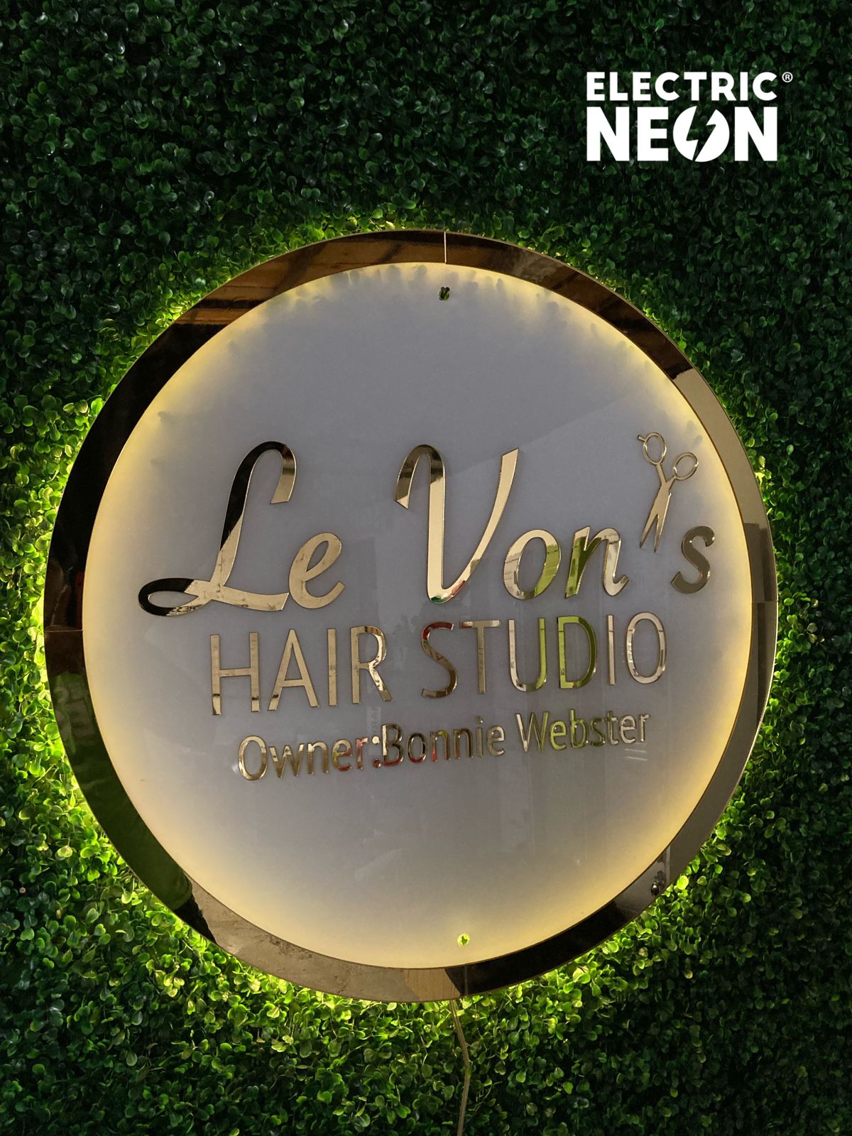 Sign for Le Von's Hair Studio on a green leafy background.