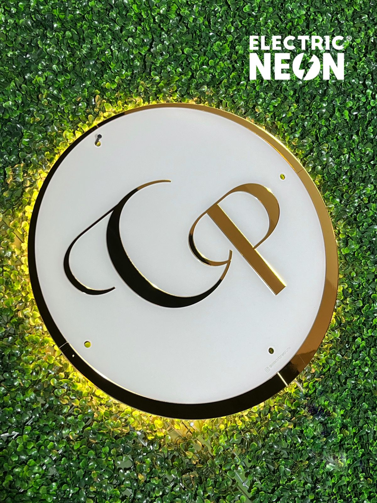 Circular logo with gold letters on a green leafy background.