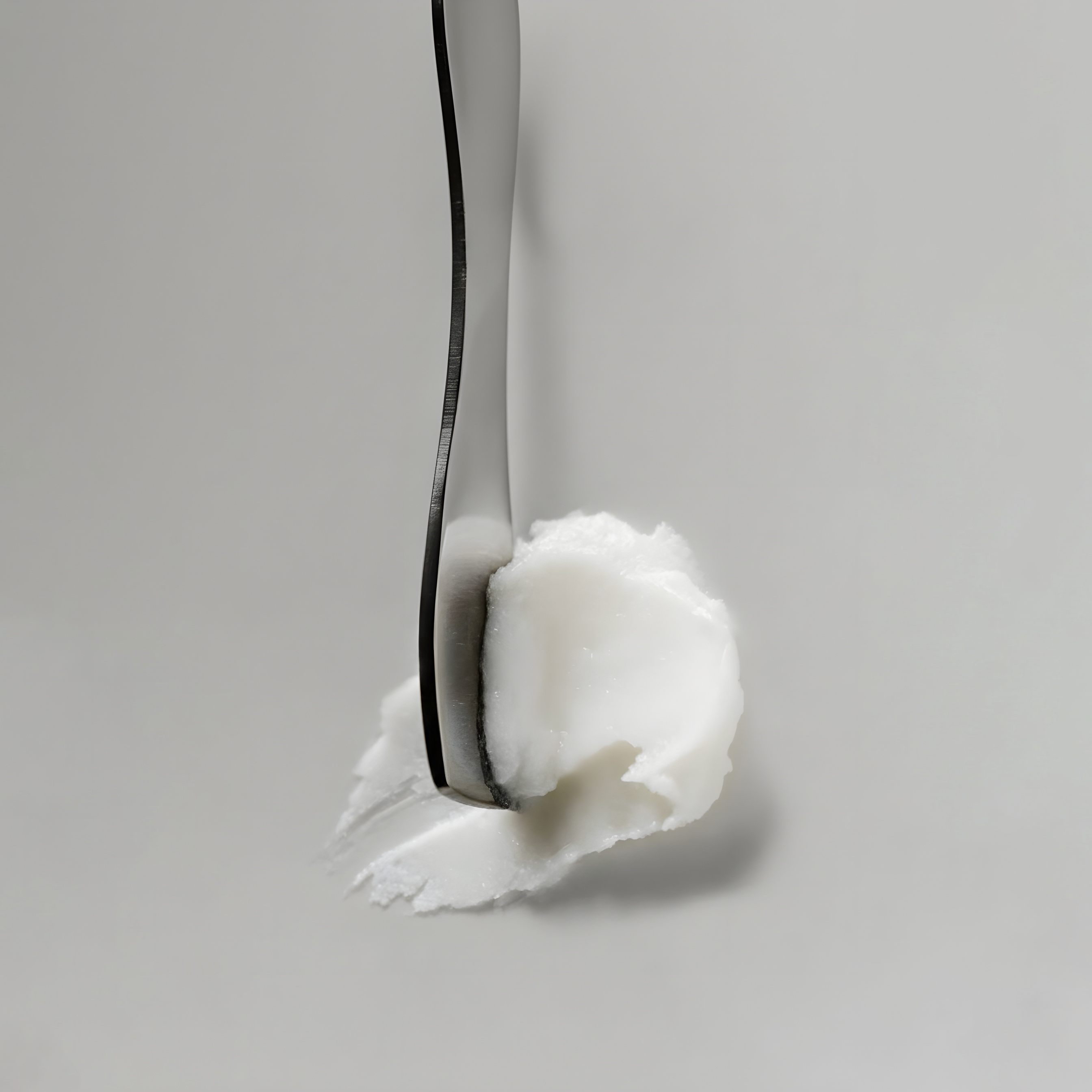 Close-up of a fork with a dollop of white substance on a gray background.