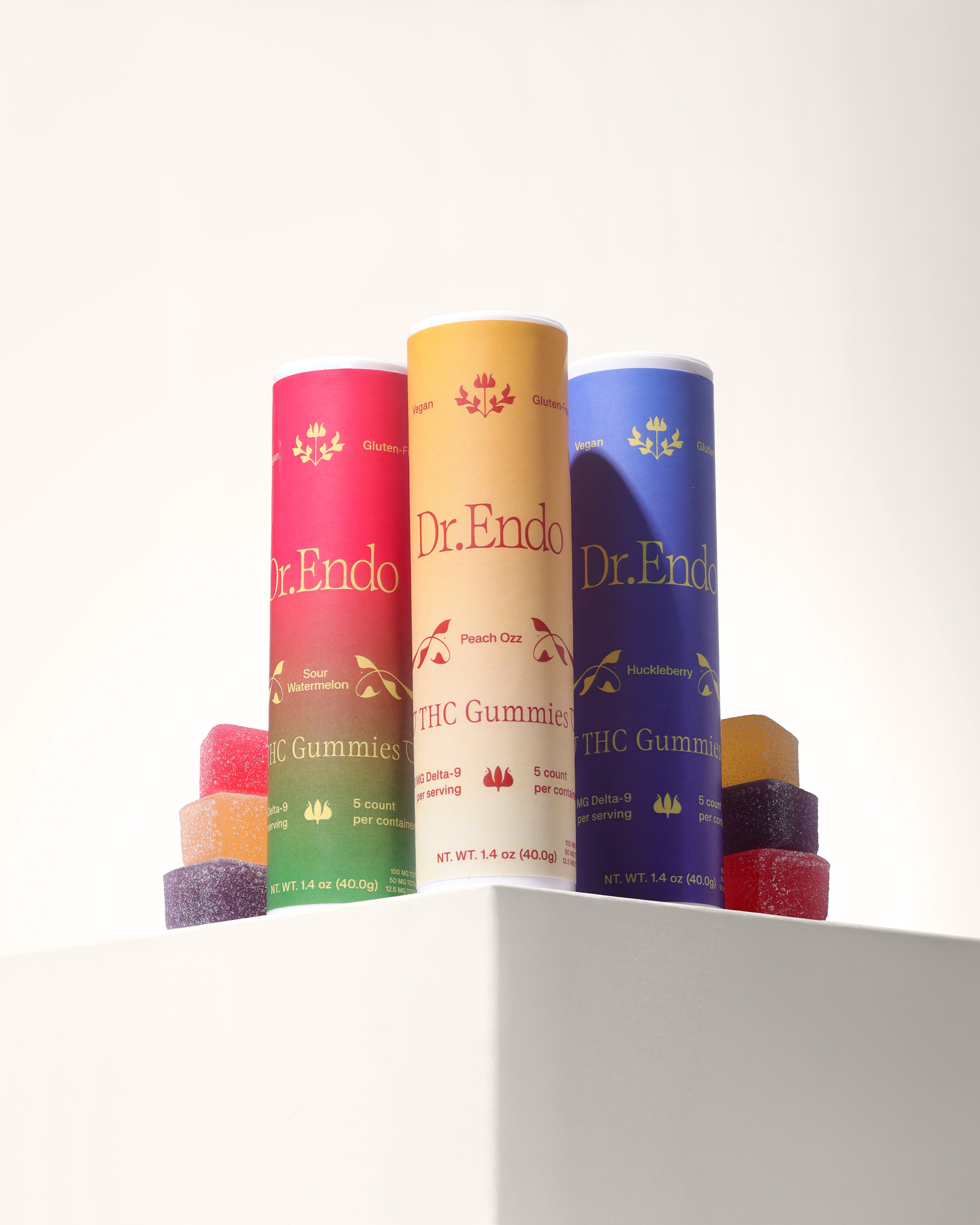 Three colorful tubes of Dr. Endo THC Gummies are displayed with several gummy cubes on a white surface.
