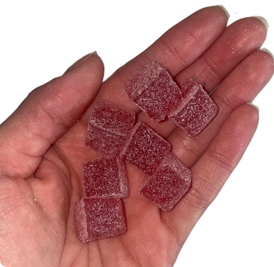A hand holding eight sugar-coated red gummy candies.