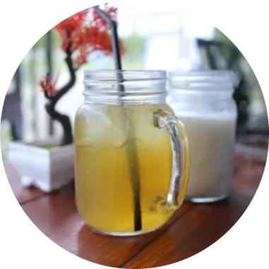 Two mason jar drinks on a wooden table, one yellow and one white.