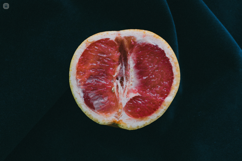 Half of a red grapefruit on a dark fabric background.