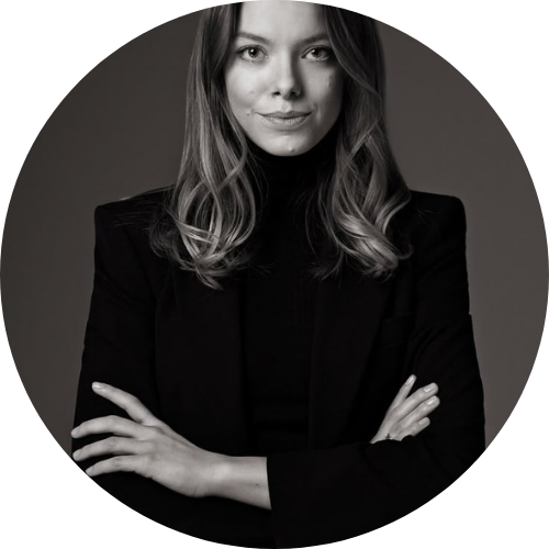 Black and white portrait of a person in a suit with arms crossed.