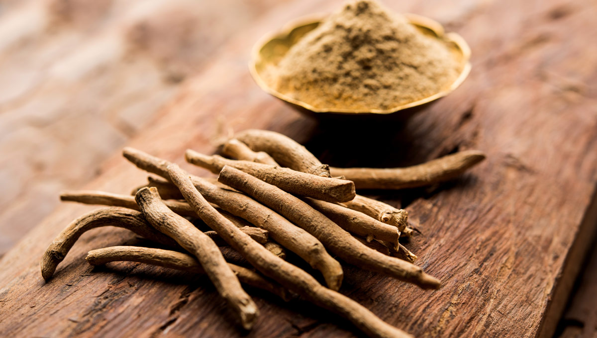 Dried roots and a bowl of powder on wooden surface.