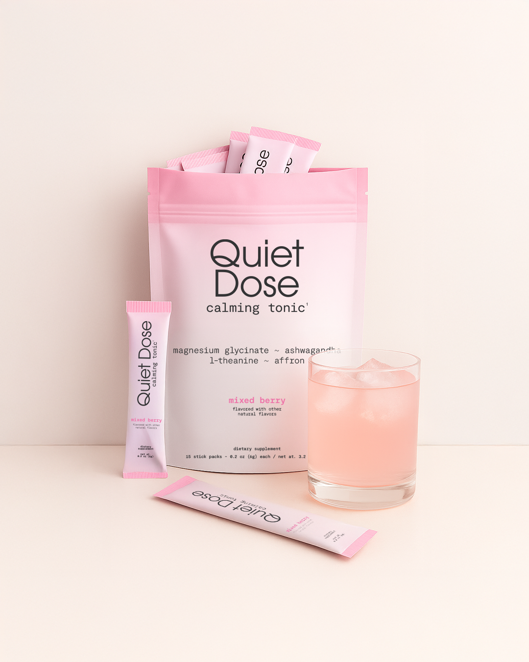 Pink sachets and drink labeled 'Quiet Dose calming tonic' on a light background.