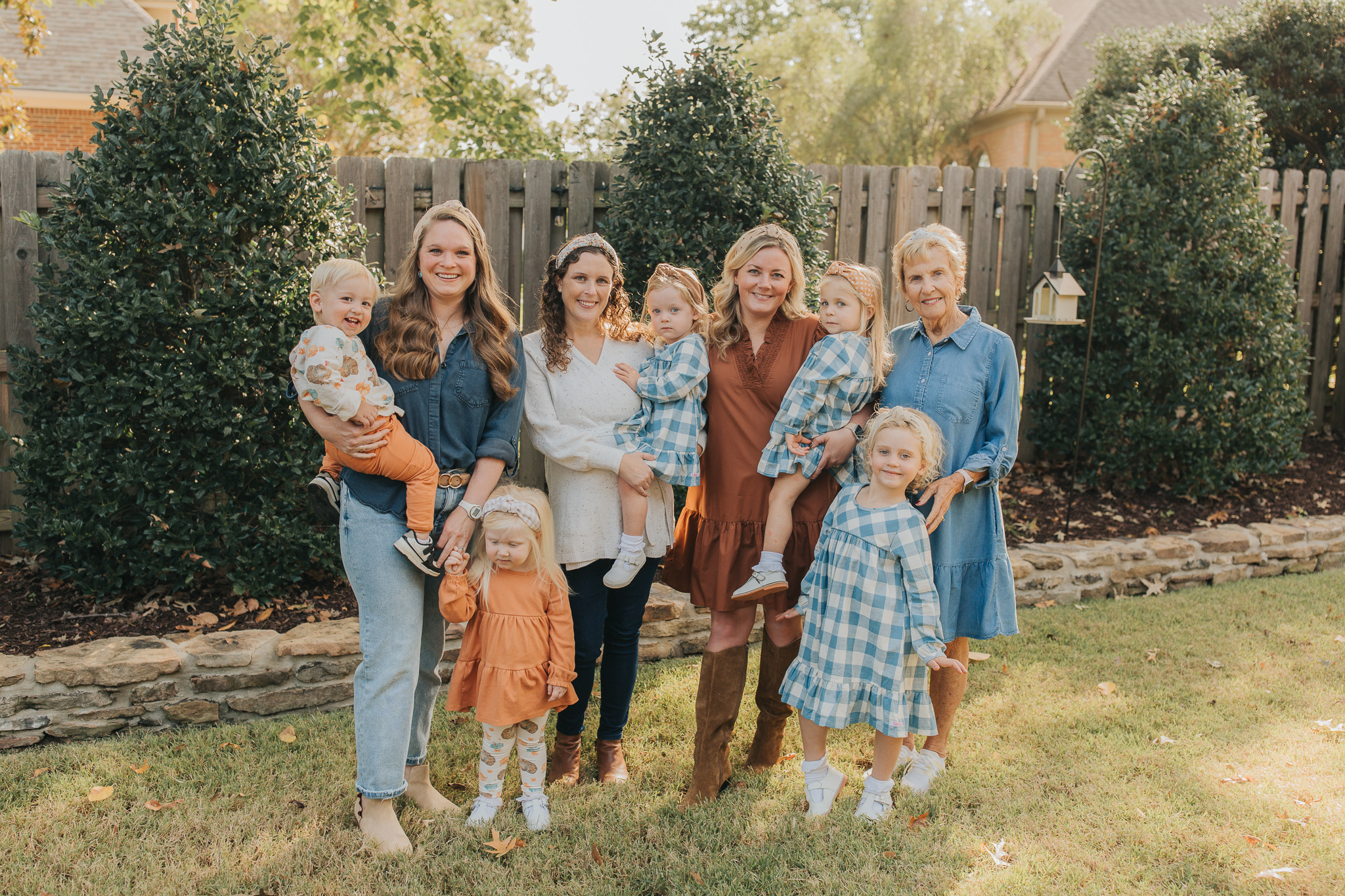 Group photo of women and children standing in a backyard.