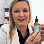 Person holding a small amber bottle with a dropper.