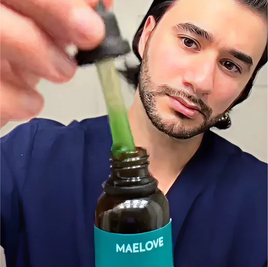 Person holding a dropper with green liquid over a bottle labeled 'MAELOVE'.