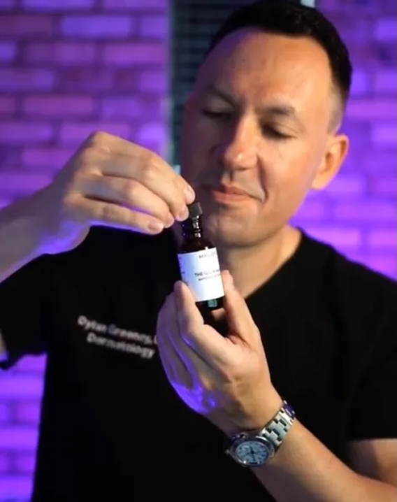 Person holding a small bottle with a dropper.