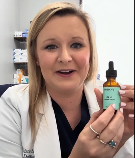 Person holding a bottle of skincare serum in an office setting.