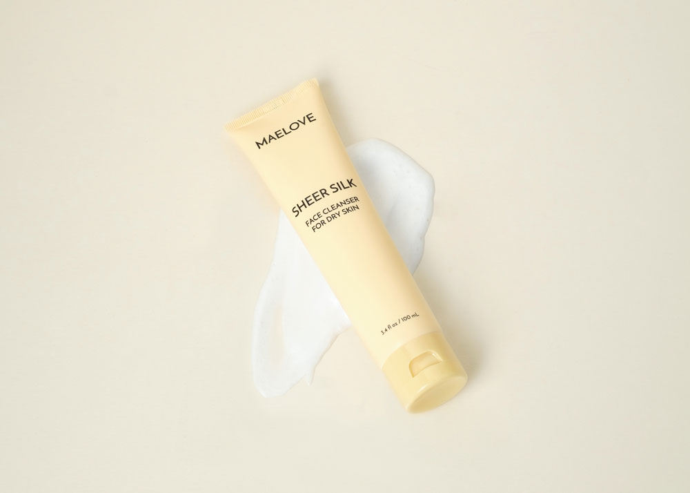 A tube of Maelove Sheer Silk face cleanser rests on a smear of white foam.