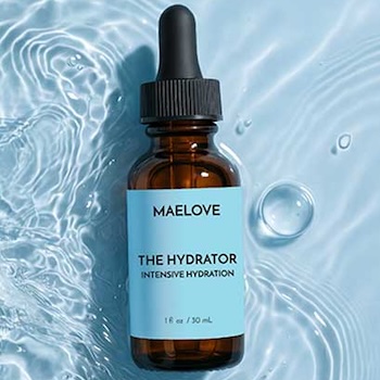 A brown bottle of Maelove The Hydrator serum with a black dropper sitting in rippling blue water.